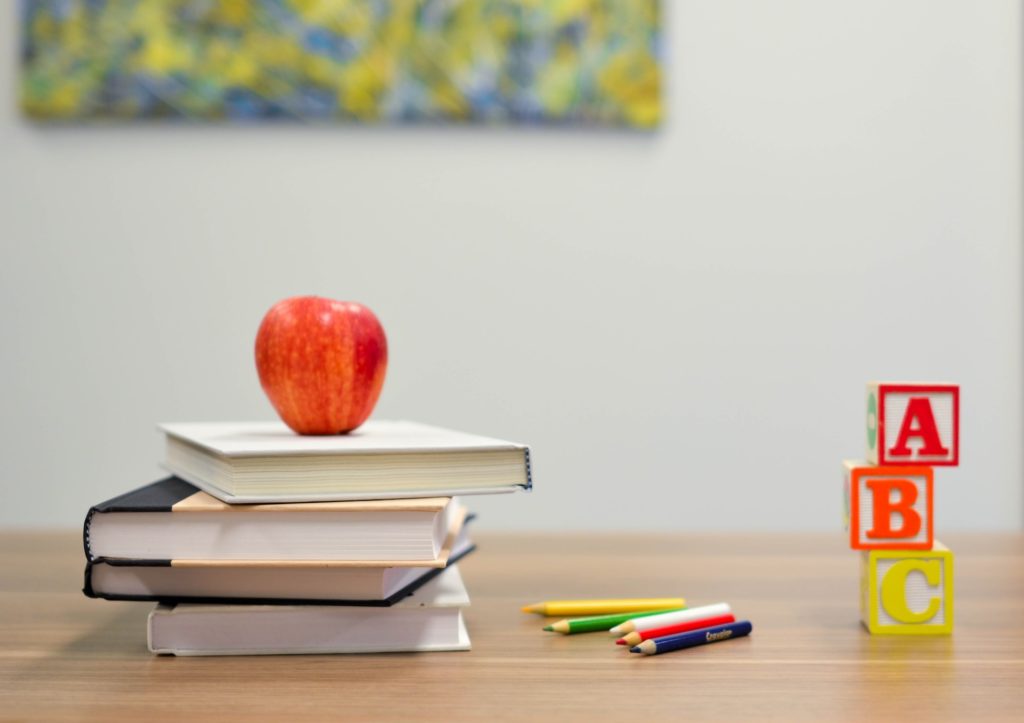 A desk with books, letter blocks and an apple for teacher to represent strategic thinking and learning